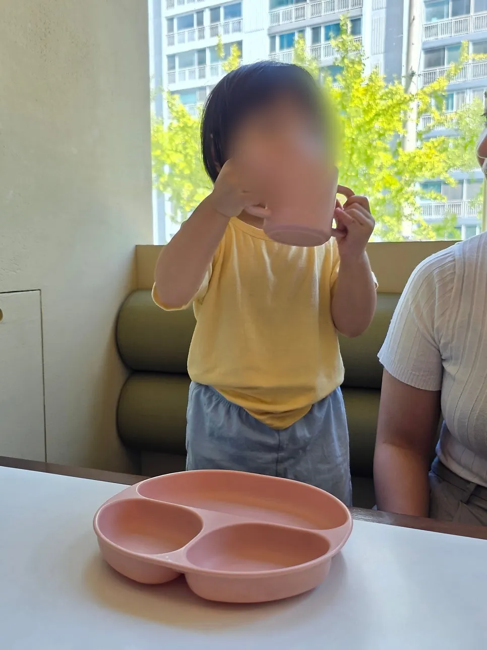 A pink baby plate and dedicated water cup for kids