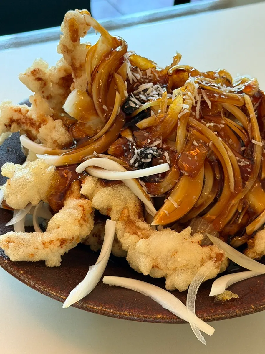 Plate of black vinegar tenderloin sweet and sour pork topped with onions