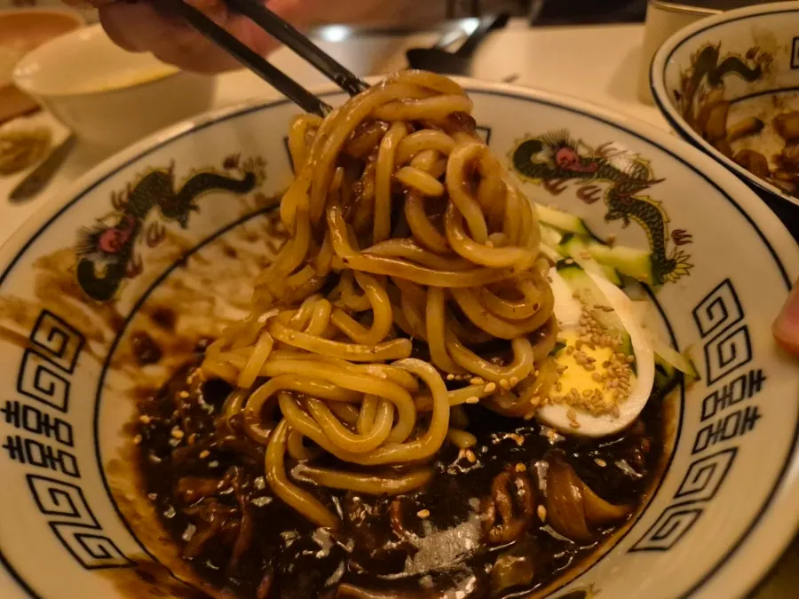 Poached-egg pork belly ganjjajang next to regular jjajangmyeon for comparison