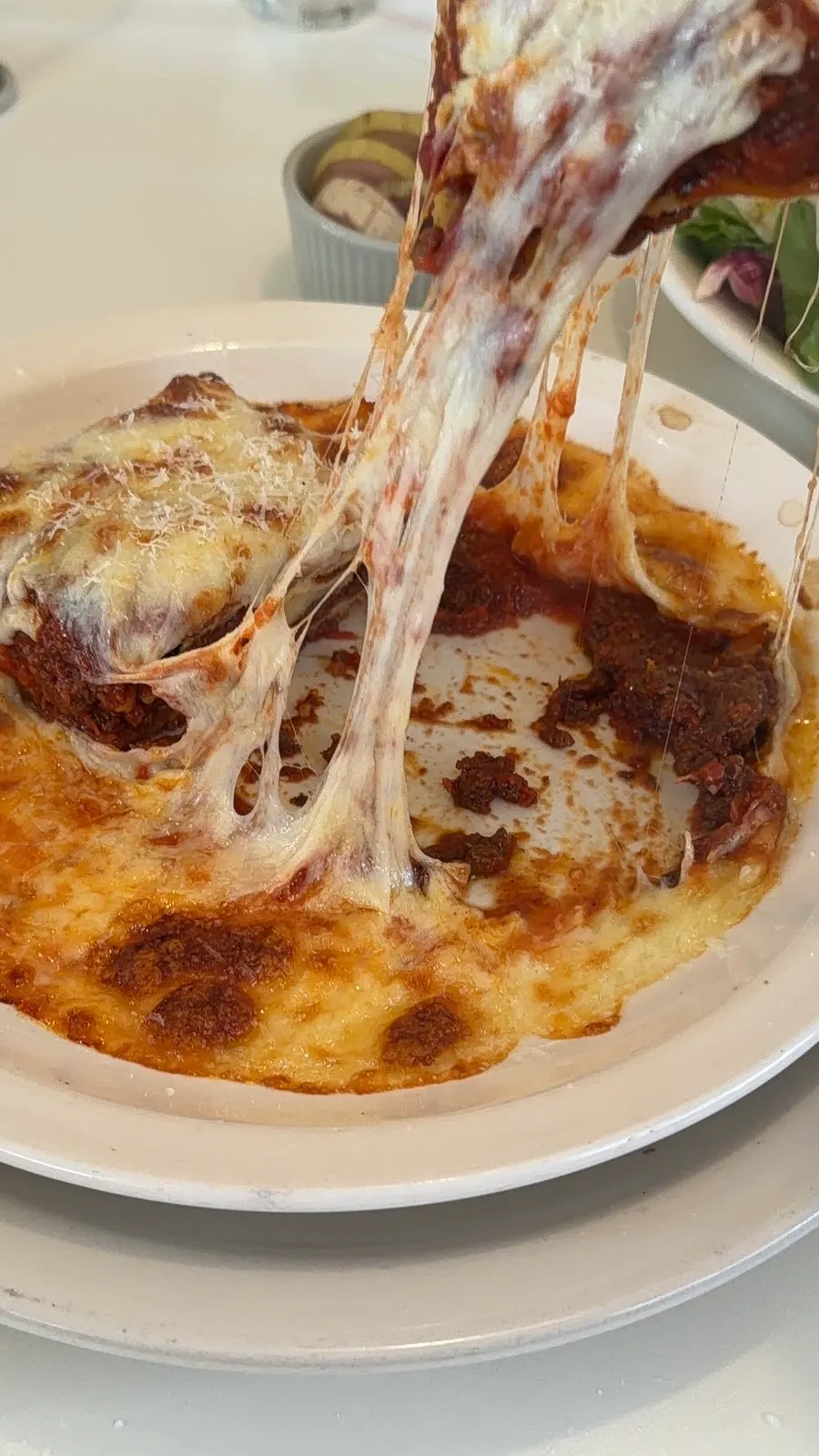 A piece of lasagna with cheese stretching long