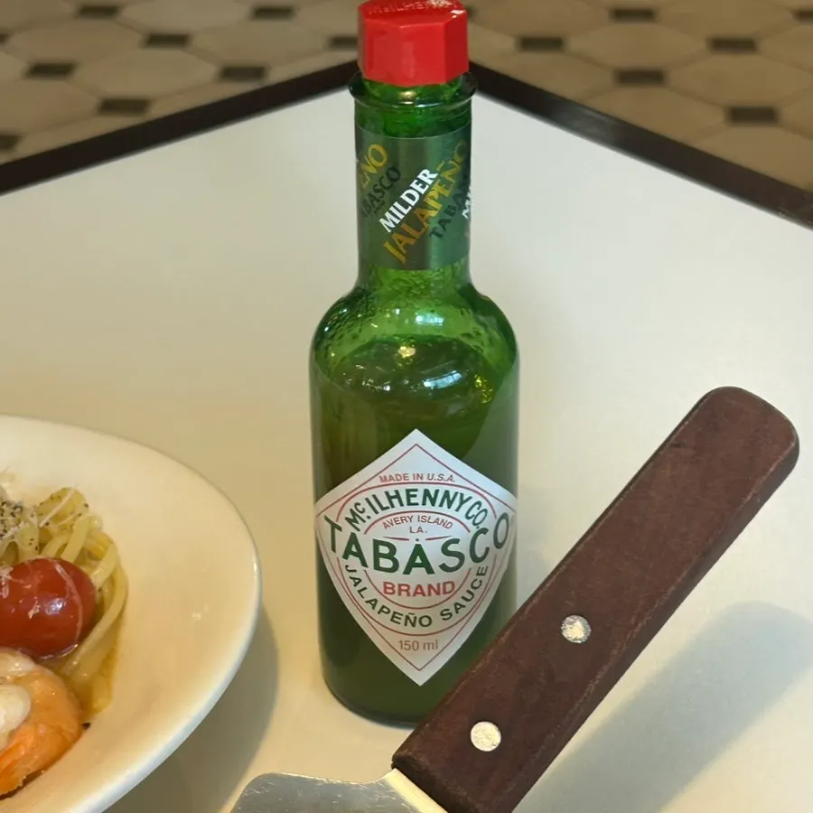 A slice of pepperoni pizza with Tabasco sauce drizzled on top