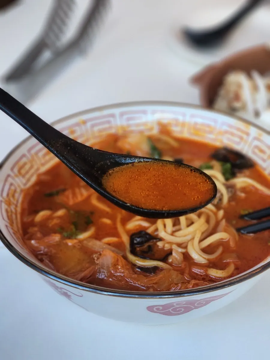 Vertical photo of jjamppong topped with mala and coriander