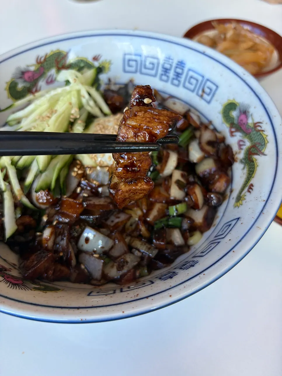Jjajangmyeon being mixed with thick-cut pork belly pieces
