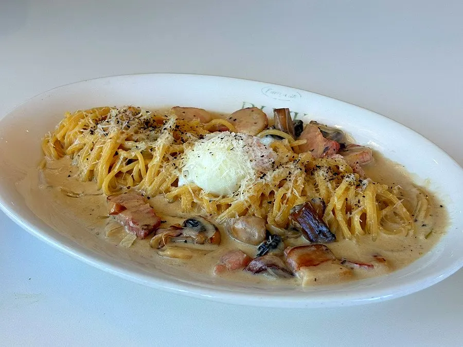 Cream pasta mixed with a broken poached egg
