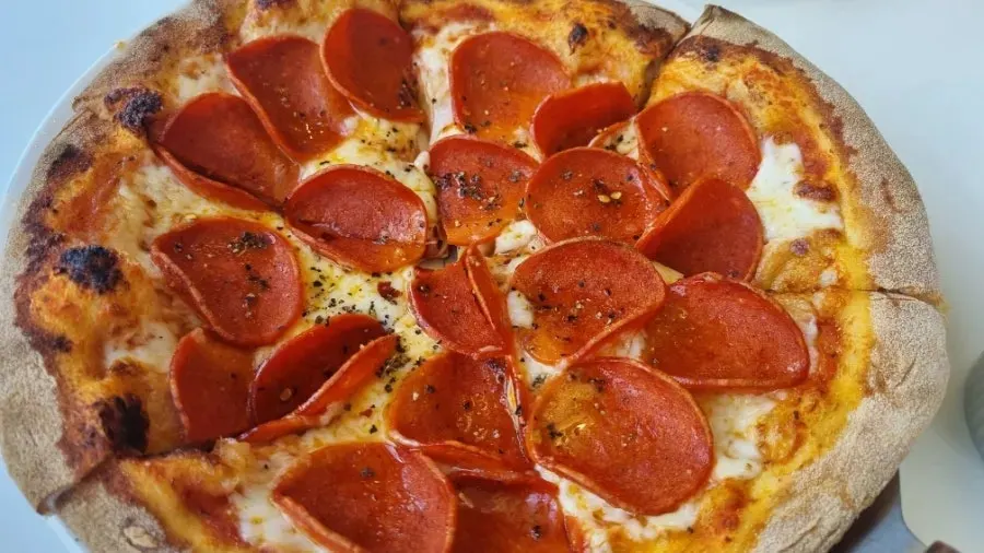 Holding up a slice of pepperoni pizza