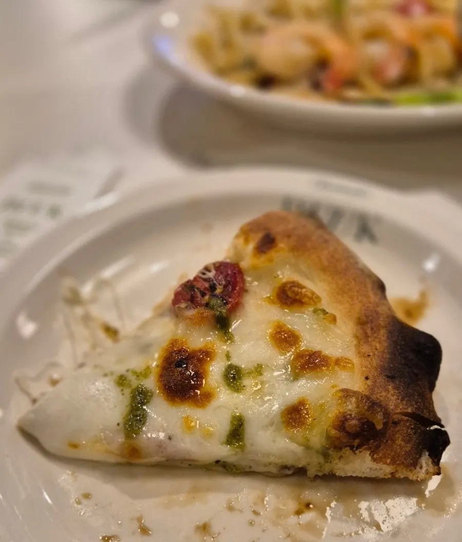 A slice of basil margherita pizza with stretching cheese