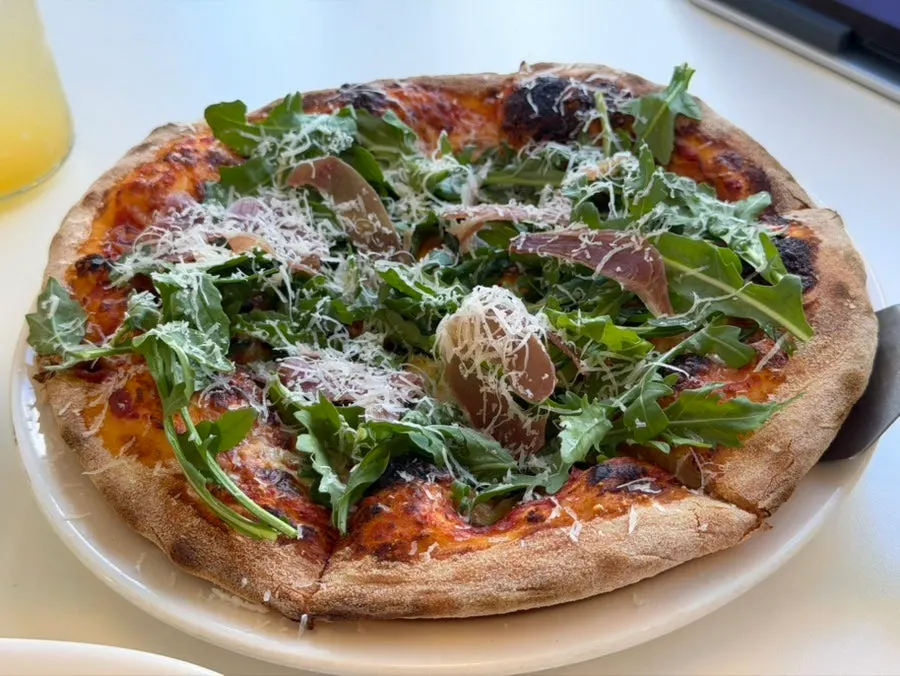 Arugula prosciutto pizza piled high with arugula