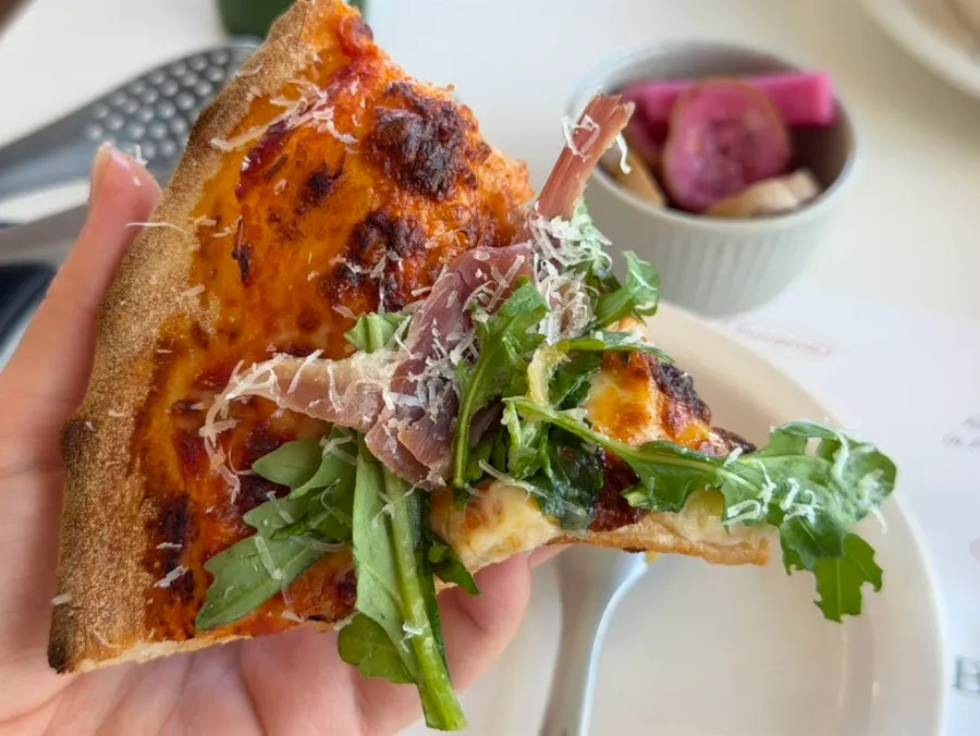 A slice of arugula prosciutto pizza