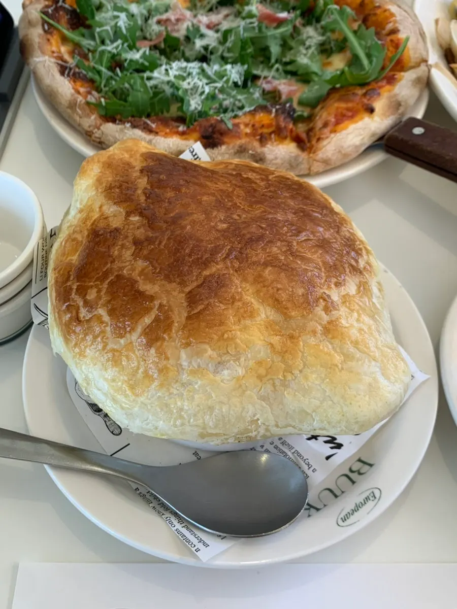 A slice of arugula prosciutto pizza with chewy dough