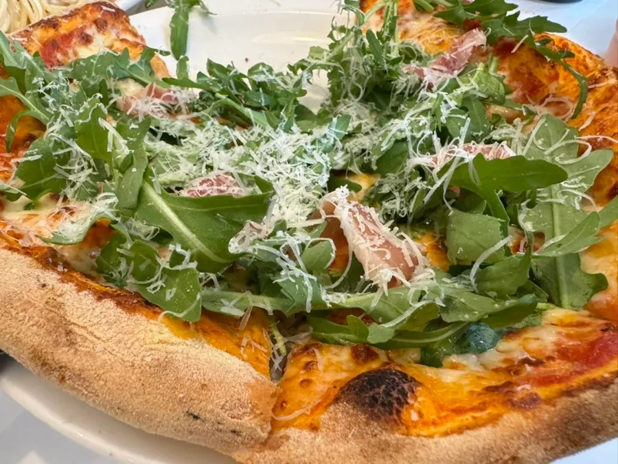 Pizza topped with arugula and prosciutto