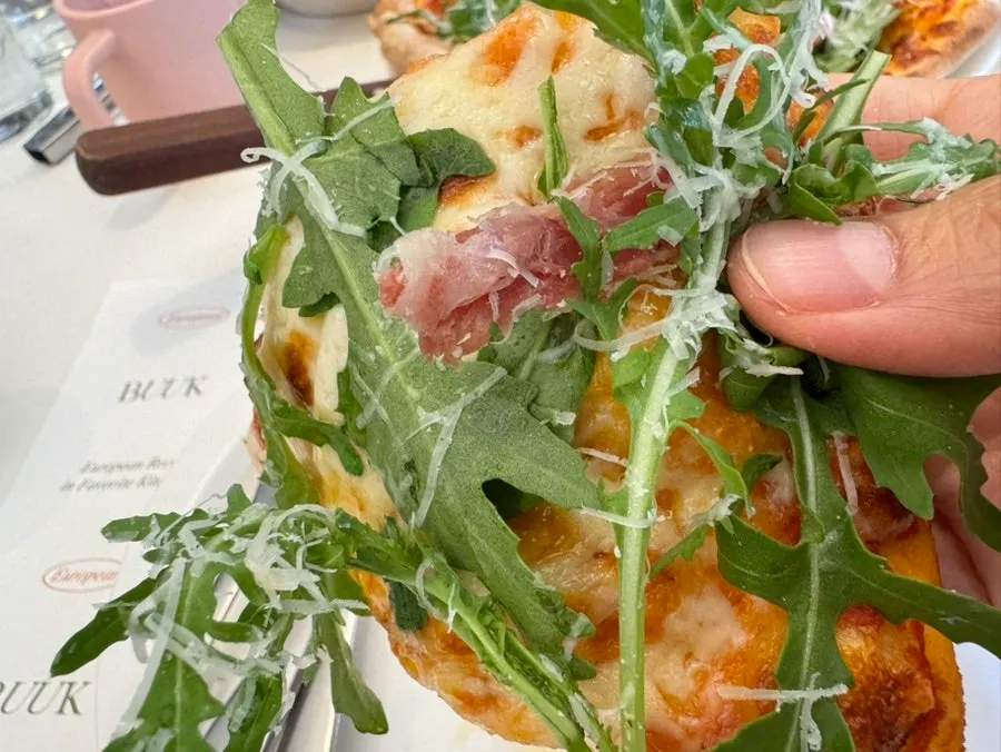 A slice lifted from the arugula prosciutto pizza