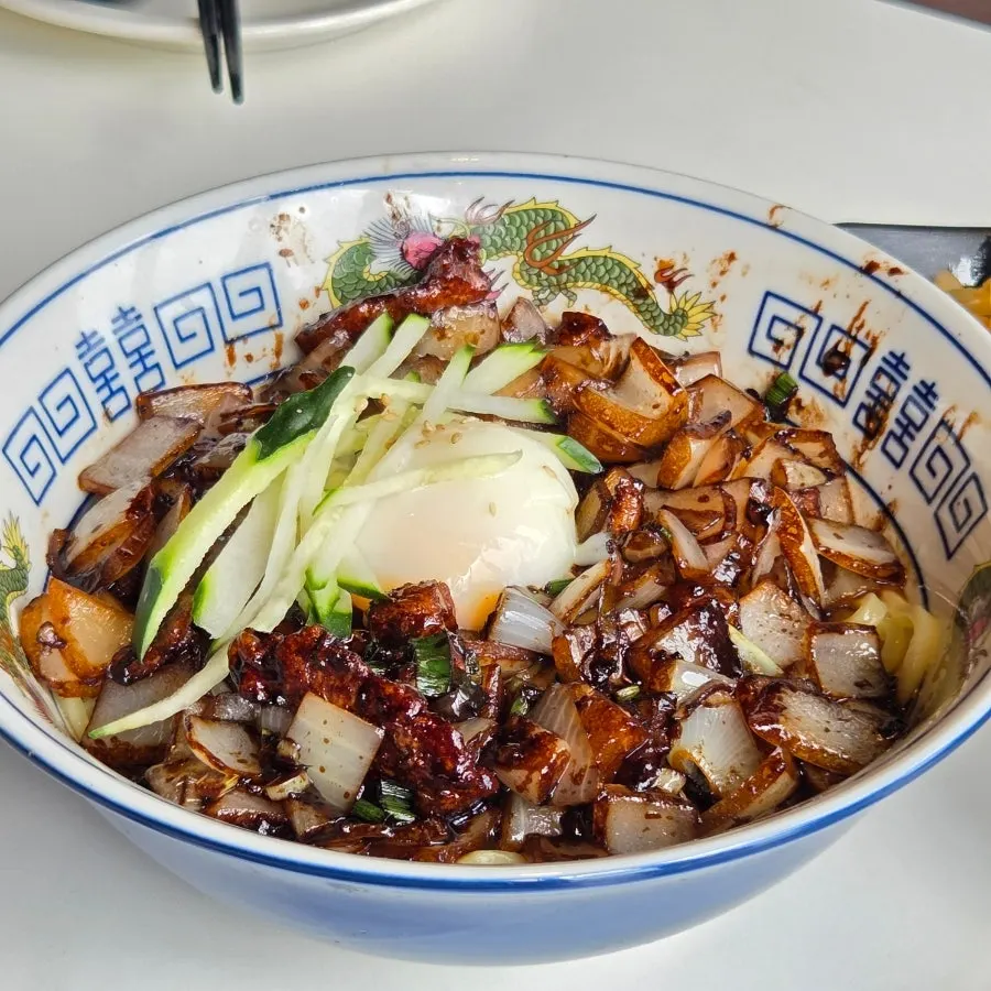 Jjajangmyeon topped with poached egg and pork belly