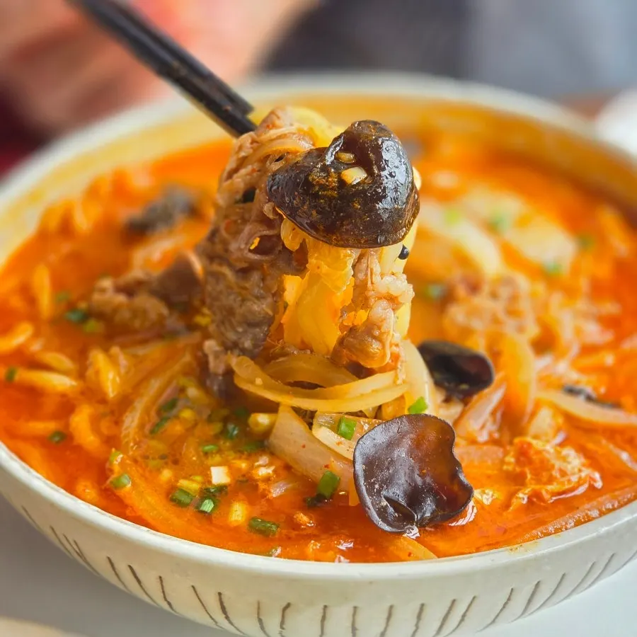 Lifting up brisket and wood ear mushroom with noodles from the jjamppong