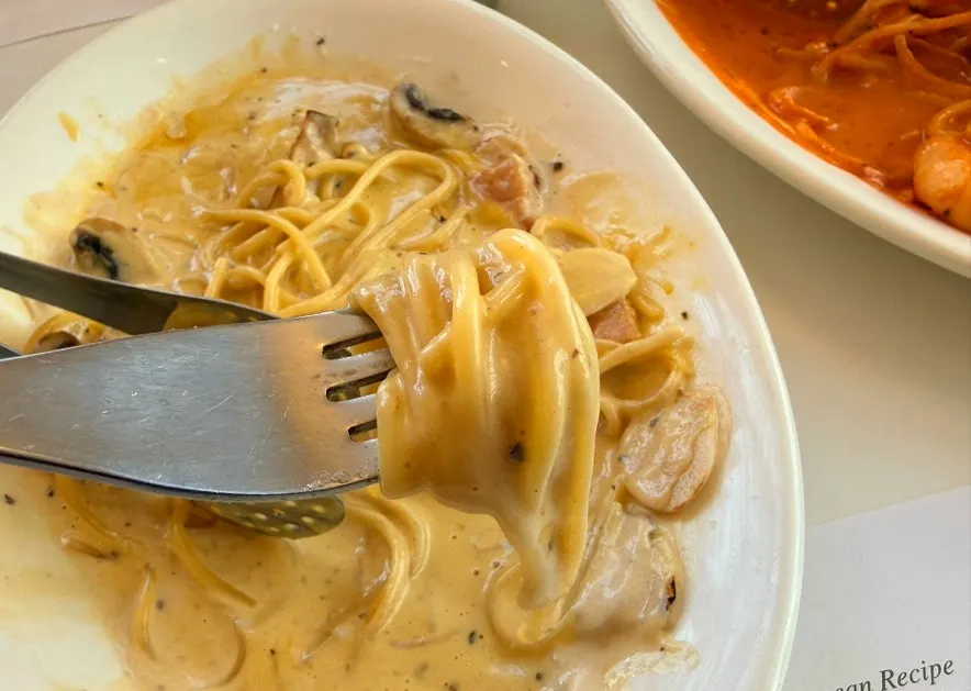A plate of carbonara showing mushrooms and bacon