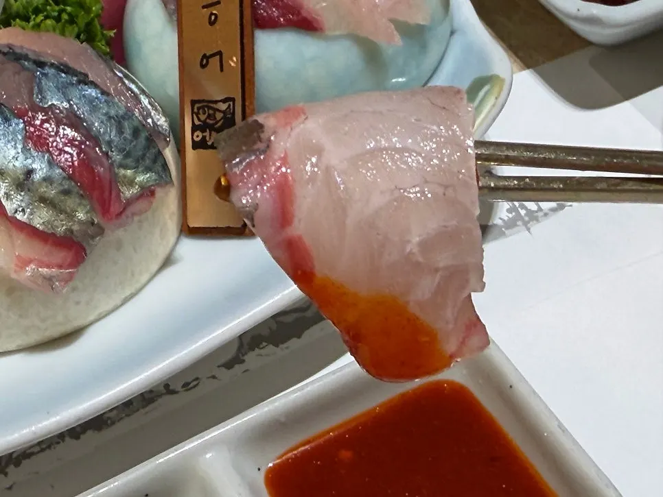 A piece of horse mackerel sashimi dipped in chojang sauce