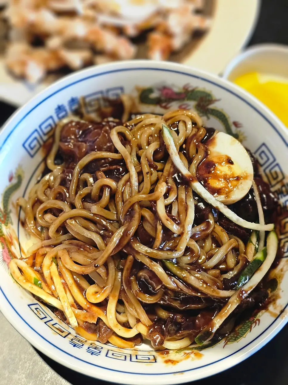 A bowl of jajangmyeon topped with cucumber and egg