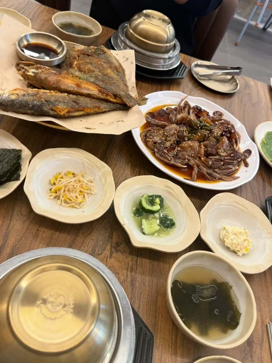 Full table spread of the grilled fish, soy crab, and pot rice set for two