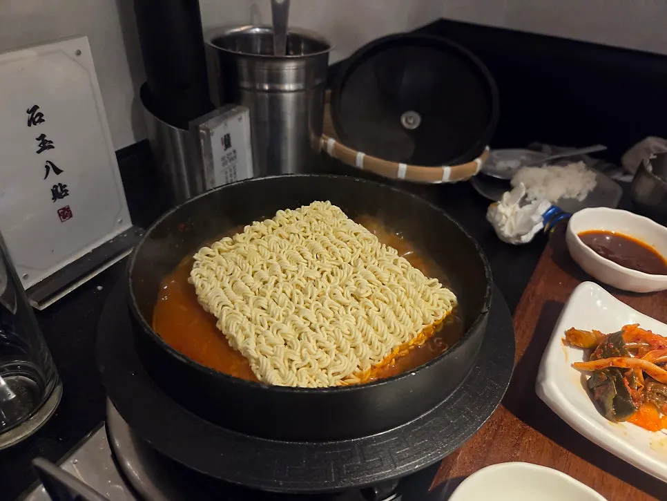 Minsaeng kimchi stew served in a pot with raw instant noodles