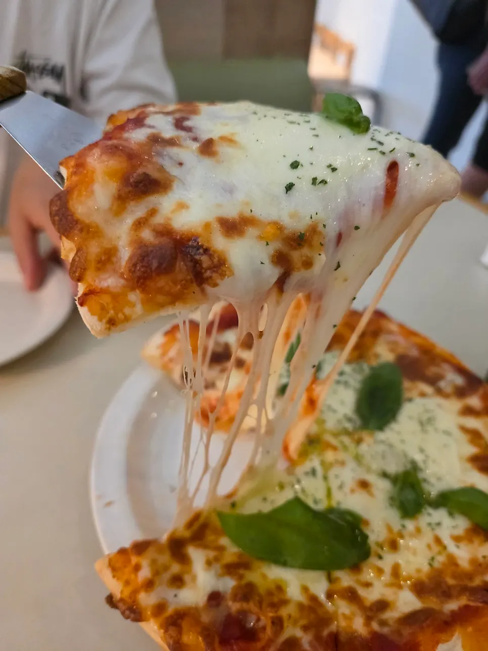 A slice of Margherita pizza with cheese pouring off