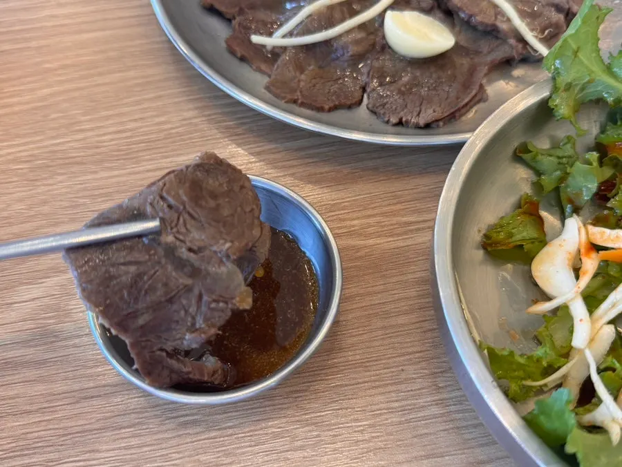 A spoonful of gomtang paired with suyuk