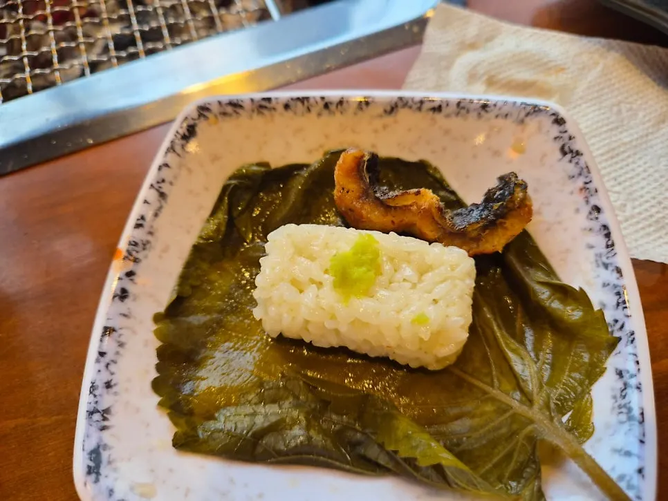A wrap of stone sushi, eel, and pickled perilla leaf