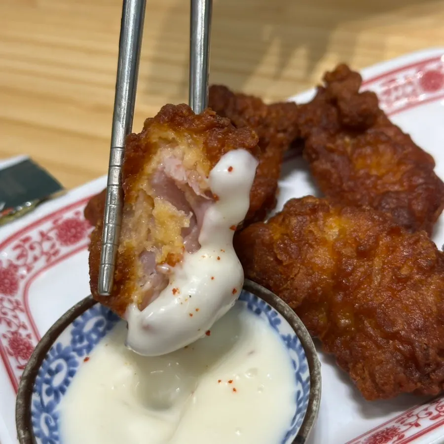 A piece of fried chicken dipped in sauce