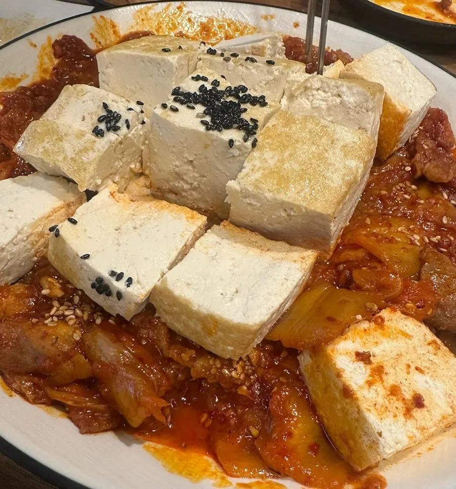 A bite of tofu topped with stir-fried kimchi