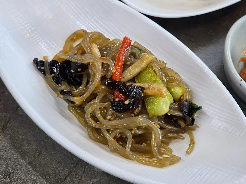 Buckwheat pancake, japchae, and dubu-kimchi side dishes