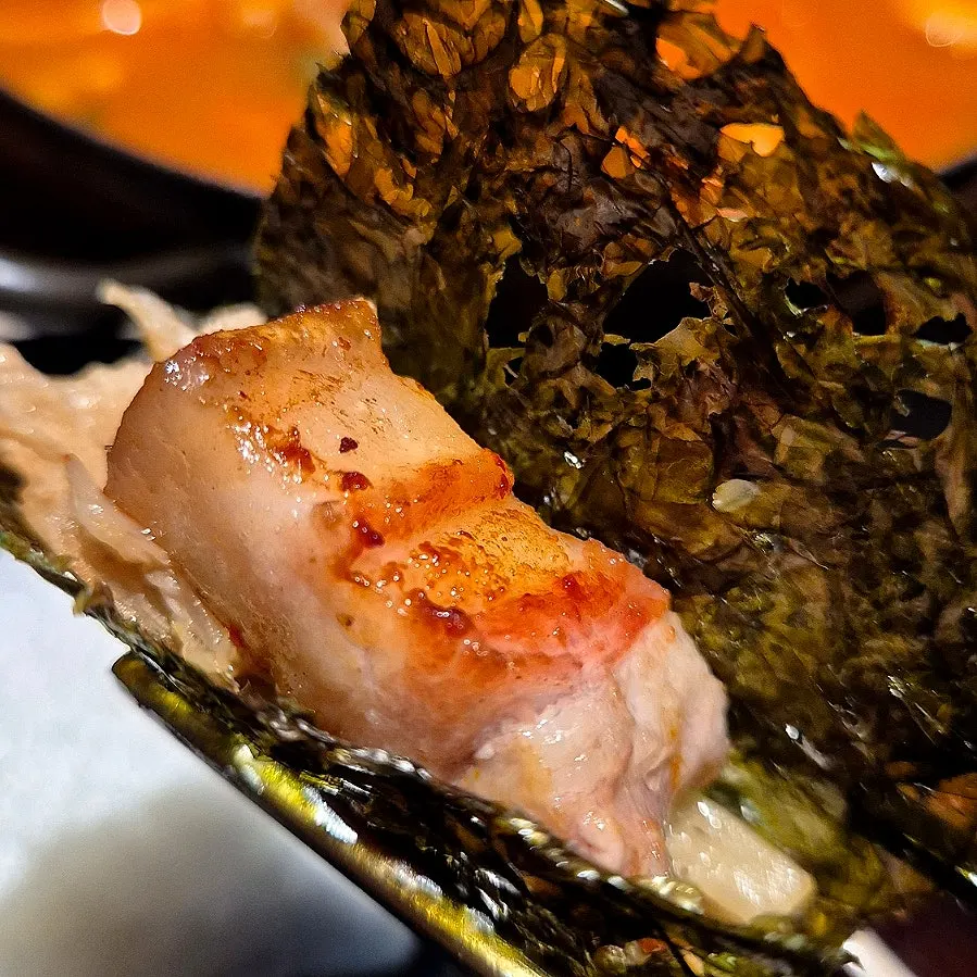 A wrap of grilled seaweed topped with roe and black pork