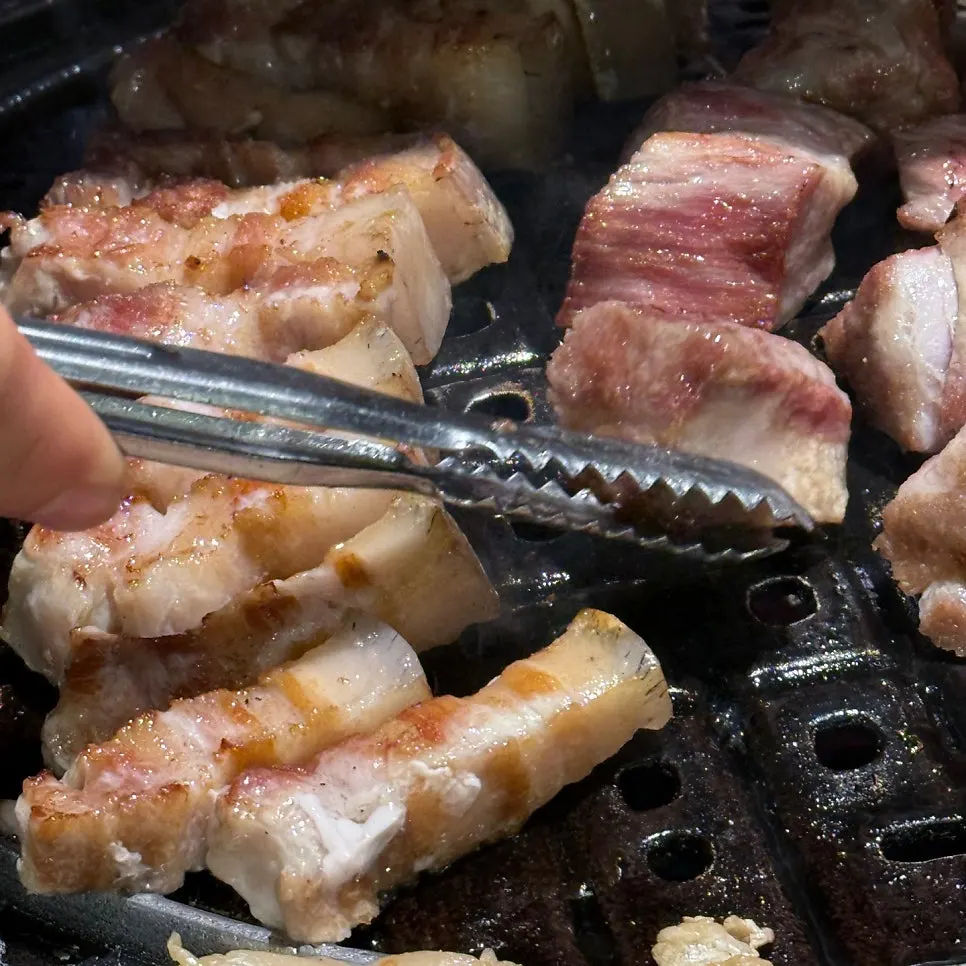 Thick piece of black pork held with tongs