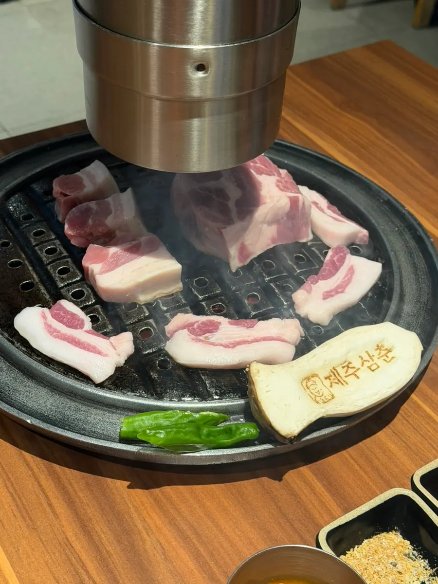 불판 위에서 겉면이 익어가는 두툼한 흑돼지