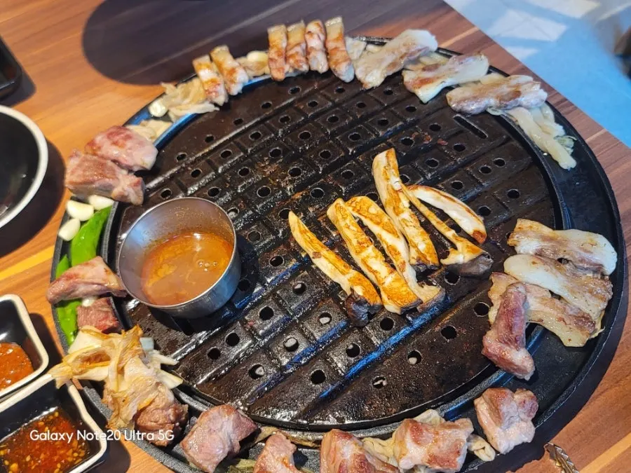 Grill full of cooked black pork and grilled vegetables