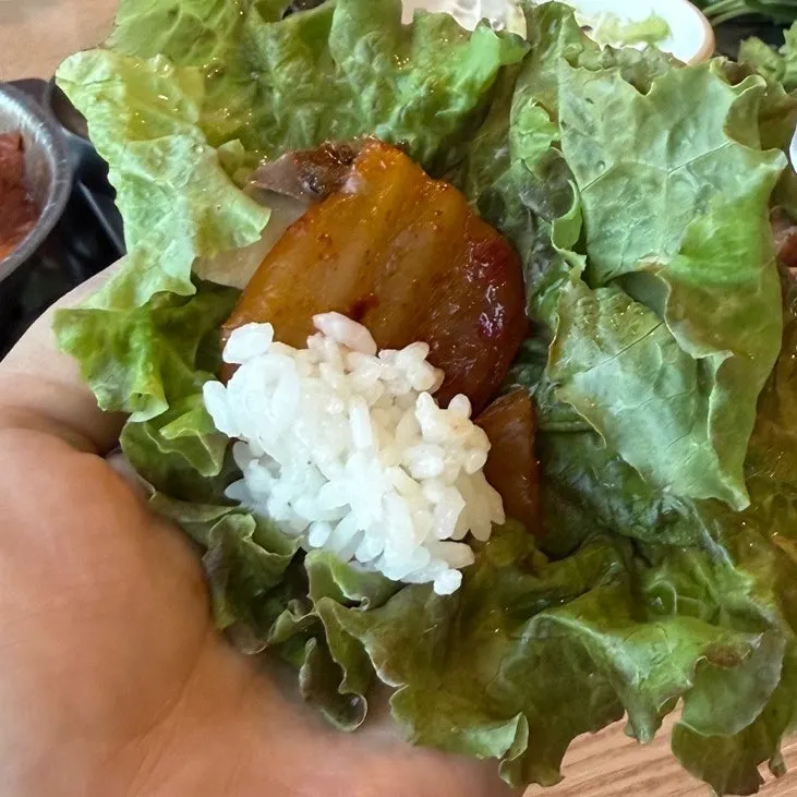 A wrap bite with rice, mackerel, and kimchi