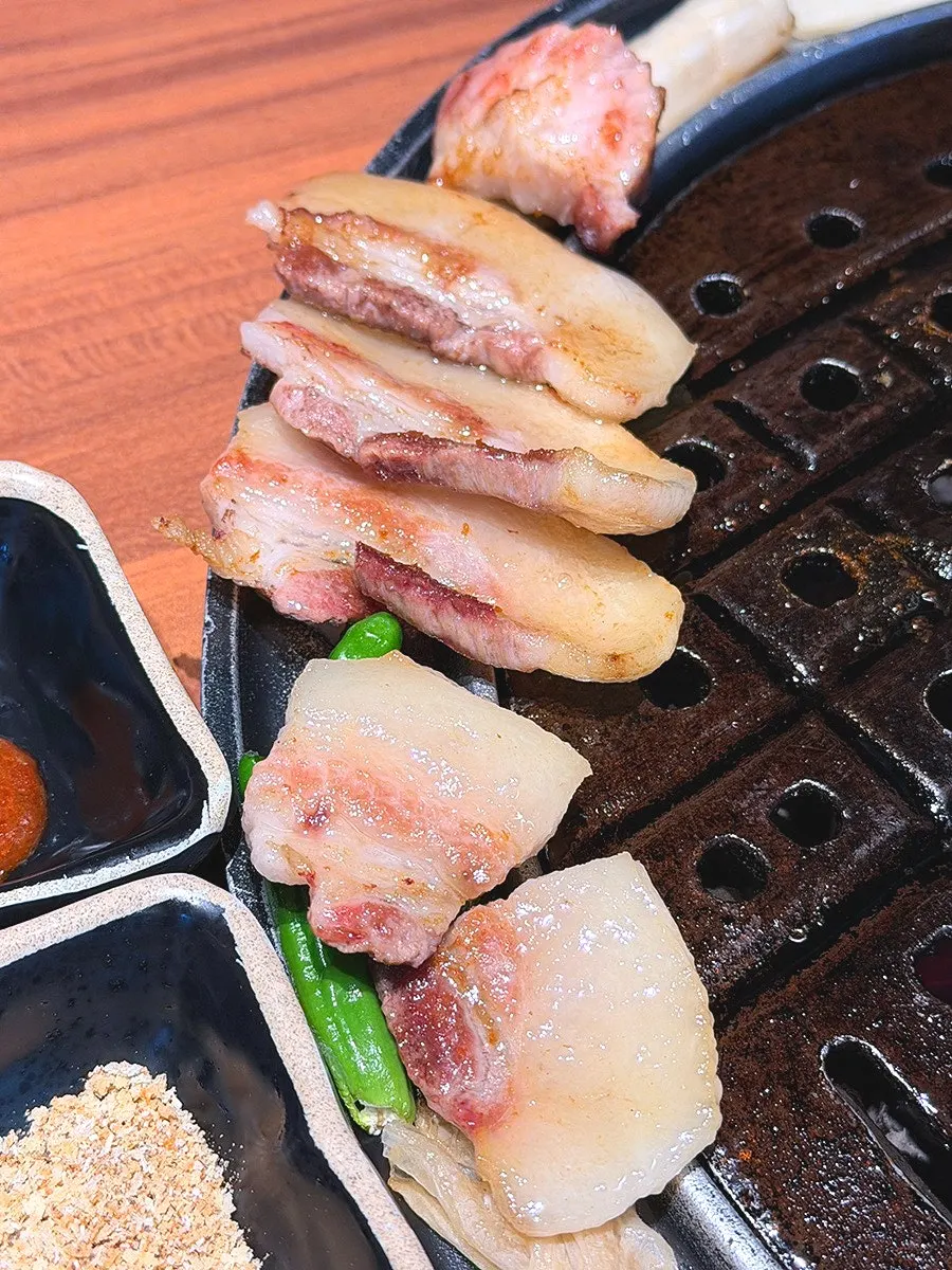 Pork neck and pork belly being grilled