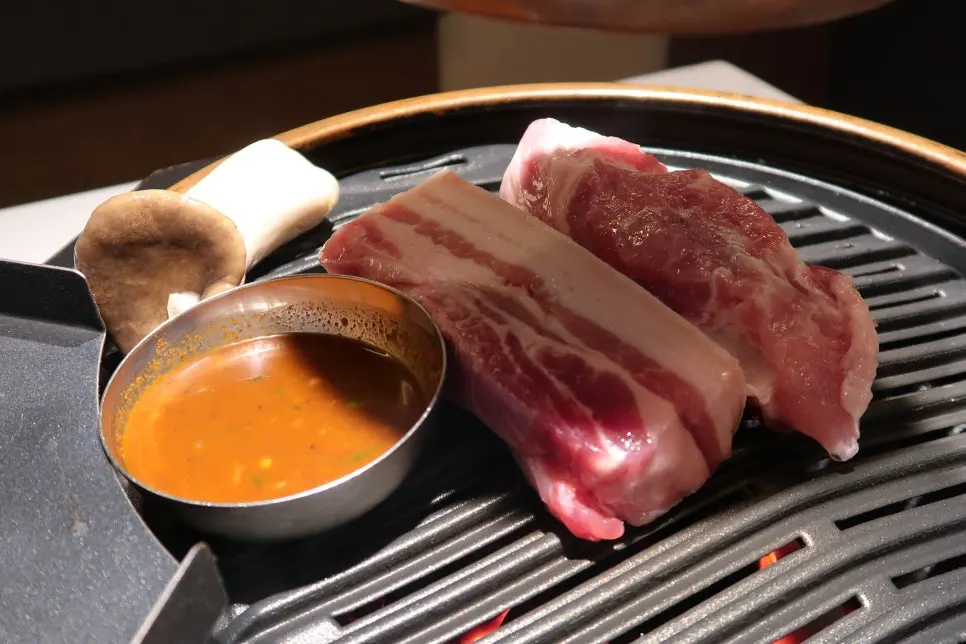 불판에서 구워지는 목살과 큼직한 버섯