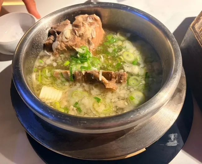 Meat set aside on the edge of the grill with minari