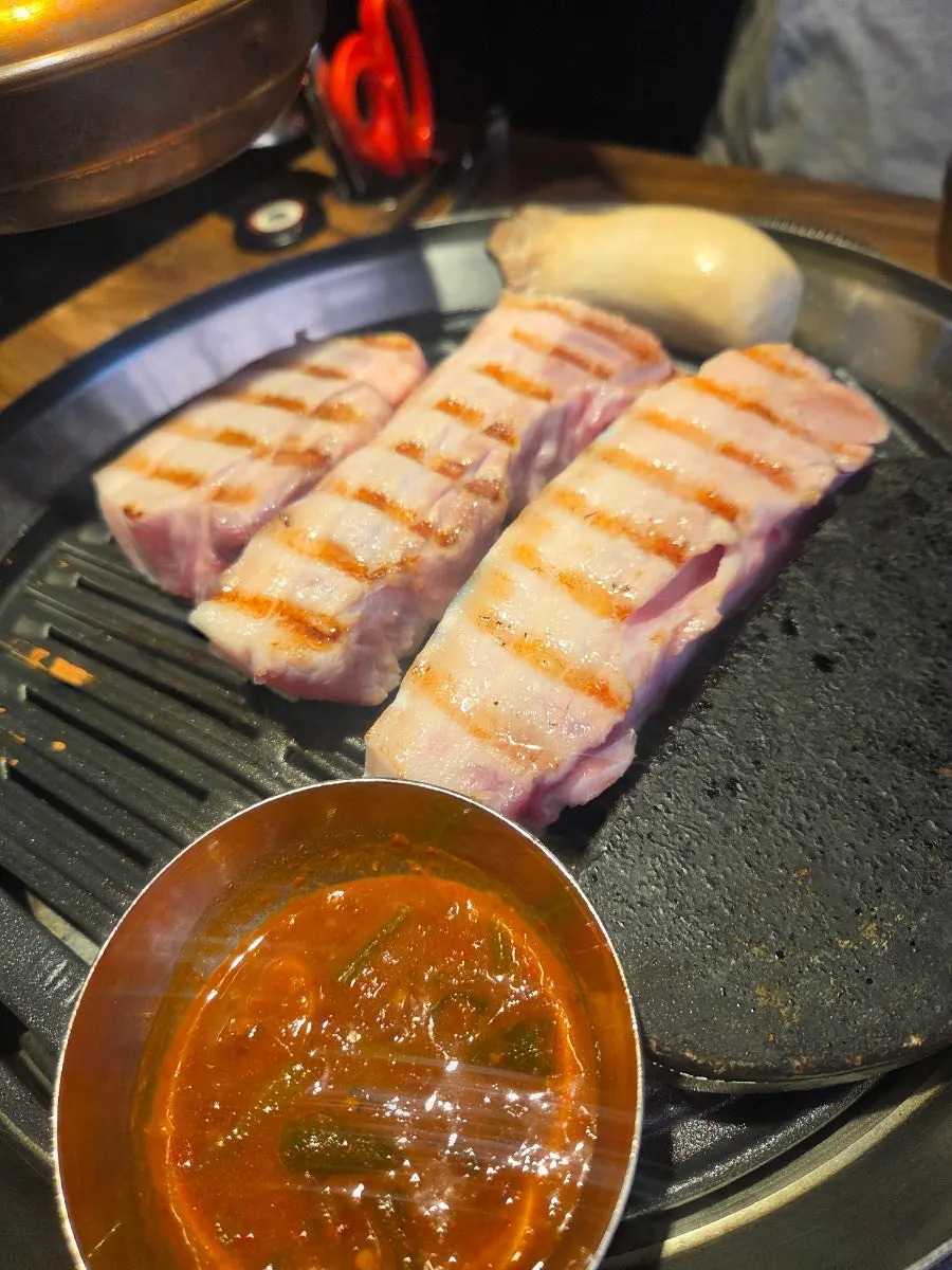 Staff member flipping the pork belly on the grill