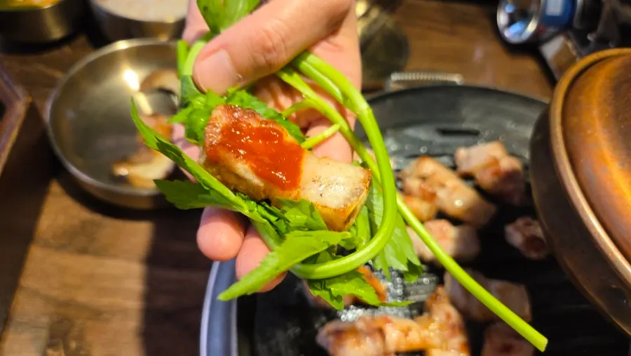 Pork belly and gochujang placed on top of a minari wrap