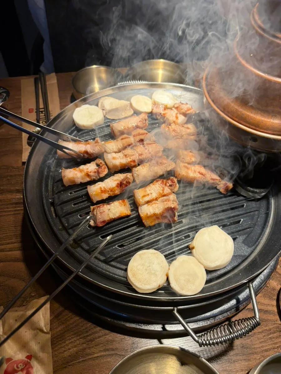 Golden-brown grilled pork belly with thin tongs