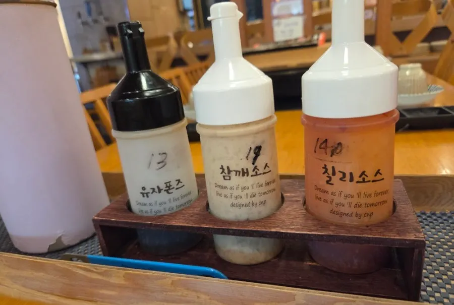 테이블에 놓인 유자폰즈와 참깨소스, 칠리소스