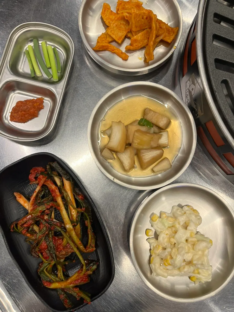 Side dishes including corn mayo salad and green onion kimchi