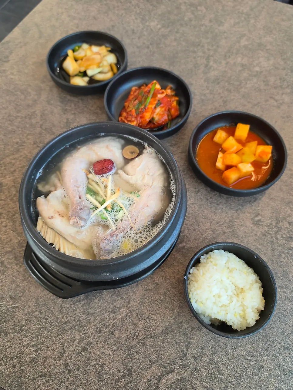 Full table setting of clear samgyetang with glutinous rice
