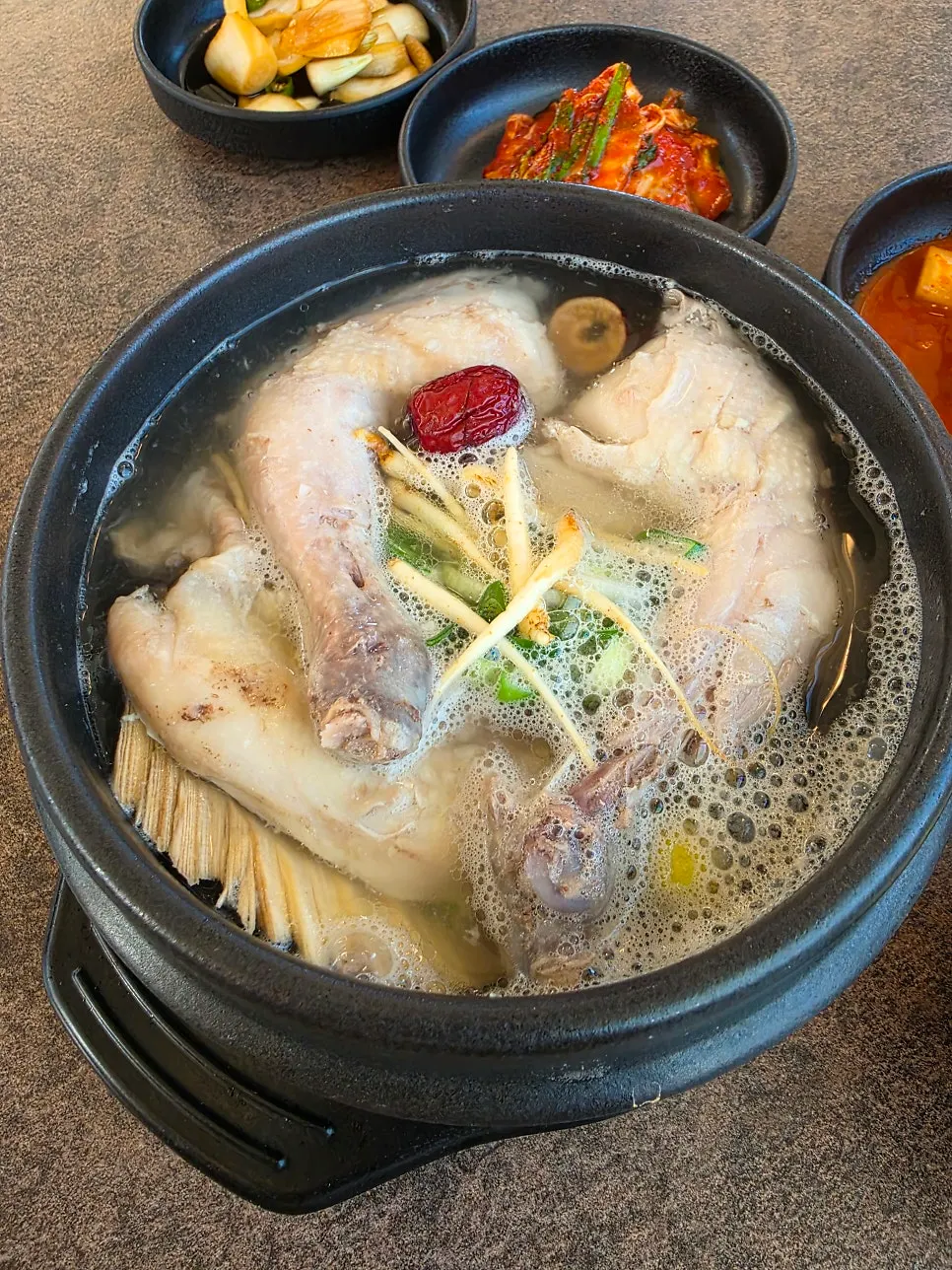 Stone pot of clear samgyetang topped with ginseng and jujube