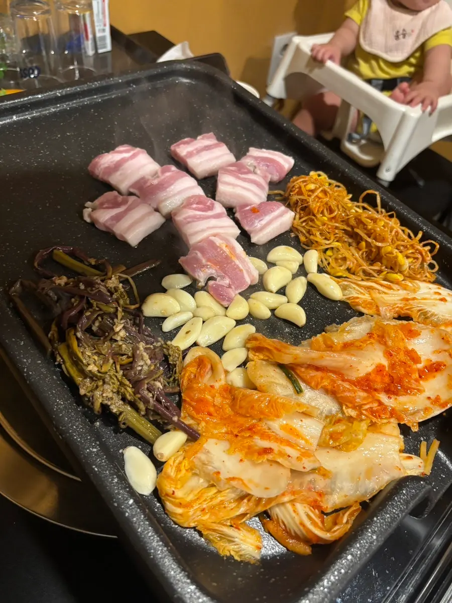 Side dishes, kimchi, and garlic grilling together on the pan