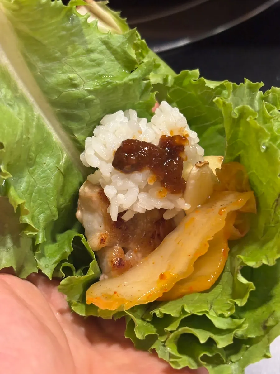 A piece of pork belly placed on a lettuce wrap