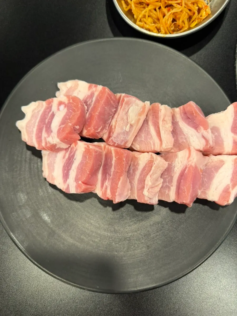 Meat grilled together with bean sprouts, bracken fern, and mustard leaf kimchi on the plate