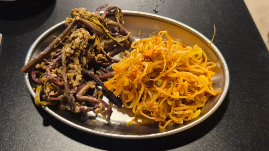 Bracken fern and bean sprouts grilling at the edge of the pan