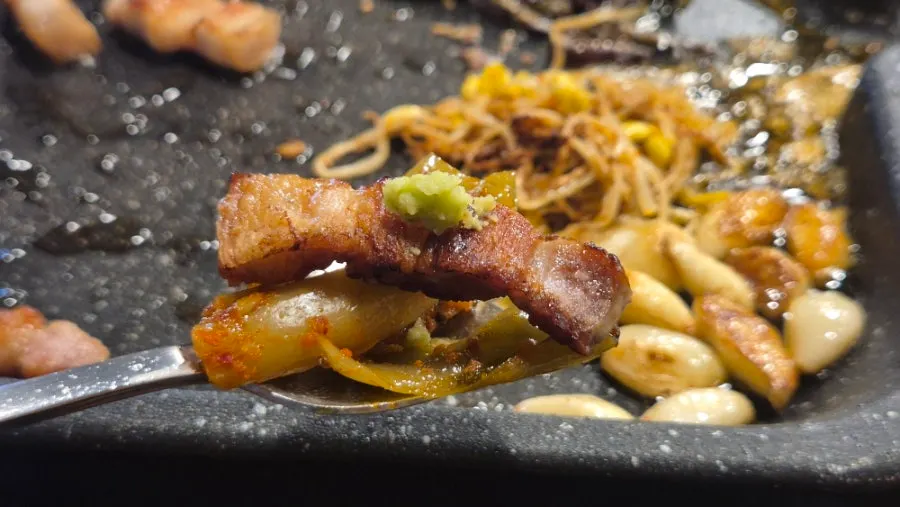 Pork belly eaten with grilled mustard leaf kimchi