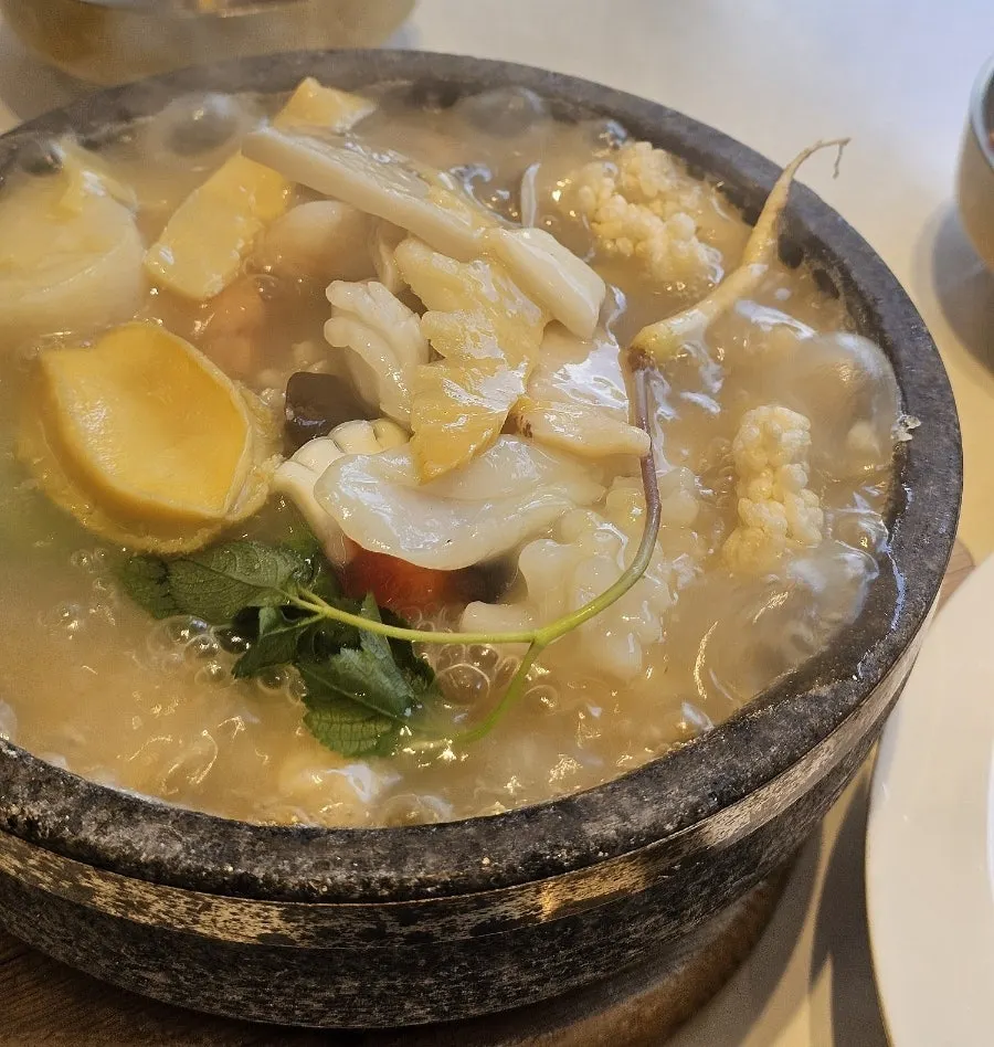 Broth being poured into the stone bowl for seafood abalone nurungjitang
