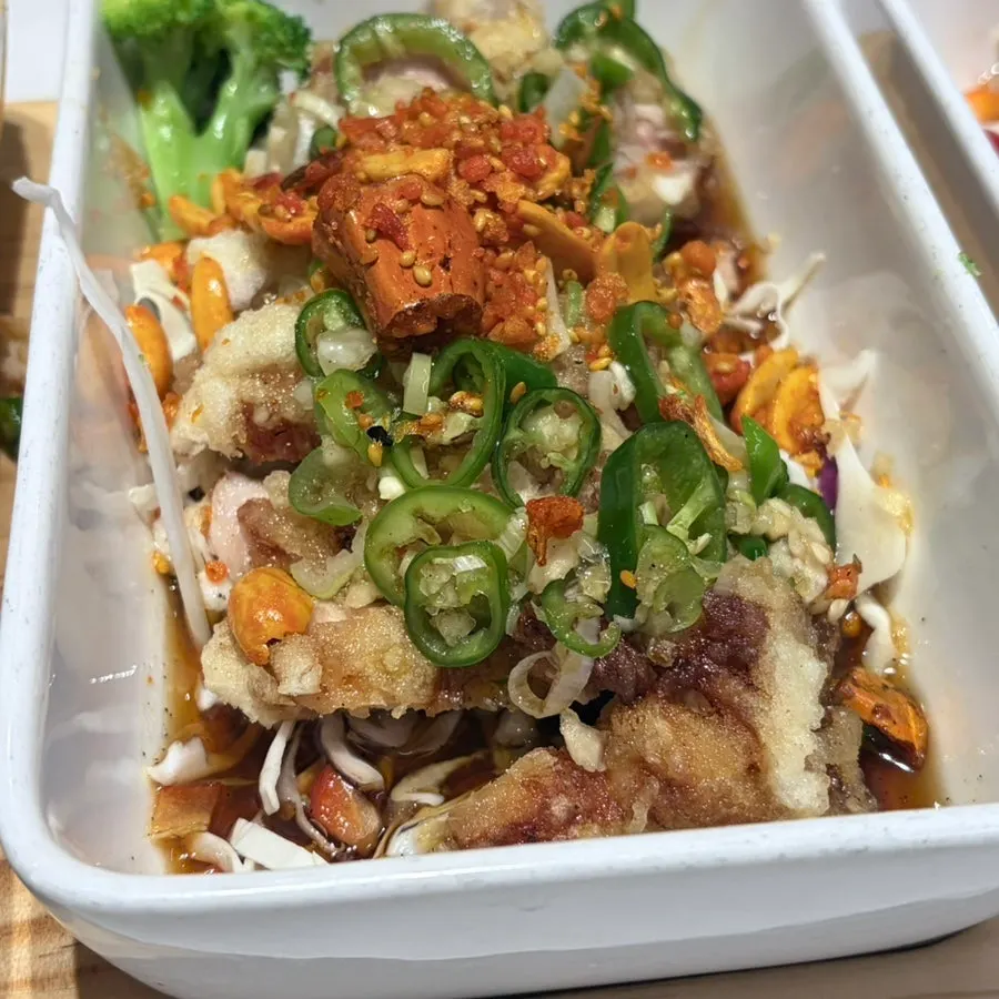 A bite of yurinki topped with sauce and vegetables
